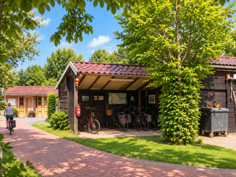 De open fietsenstalling met een rij fietsen onder de overkapping, met de plattegrond aan de wand