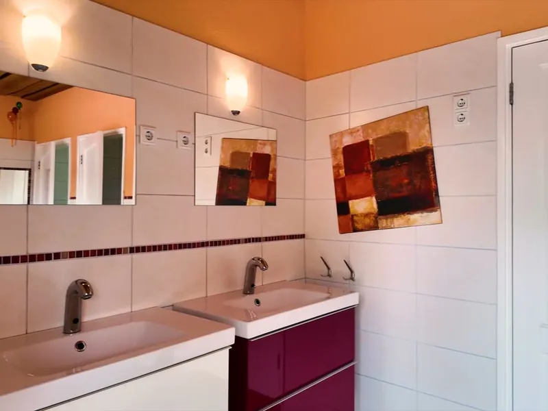 Het sanitairgebouw van binnen, met tegelvloer en houten deuren