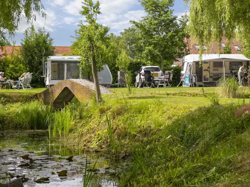 De vijver met het bruggetje, met daarachter de kampeerplaatsen