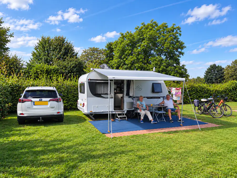 Een comfortplaats met caravan, uitgeschoven luifel en de auto ernaast