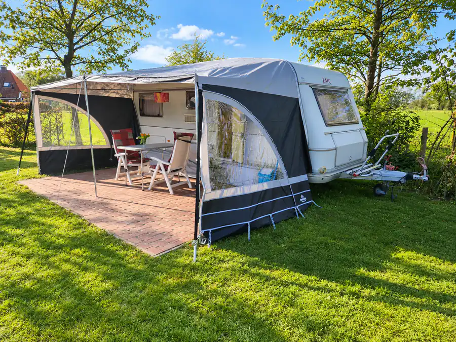 De huurcaravan met uitgeklapte luifel, tafel en stoelen op het terras