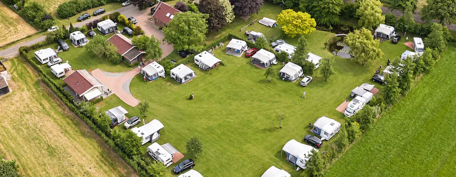 Luchtfoto van Camping de Kei, met caravans en voortenten rond het open kampeerveld