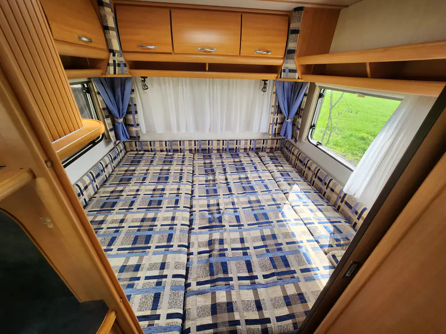 Het bed van de huurcaravan, opgemaakt als kingsize tweepersoonsbed