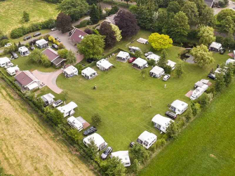 Het hele terrein van Camping de Kei van bovenaf, met caravans rond het open grasveld
